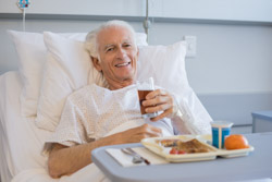 Älterer Mann isst zu Mittag im Klinikbett